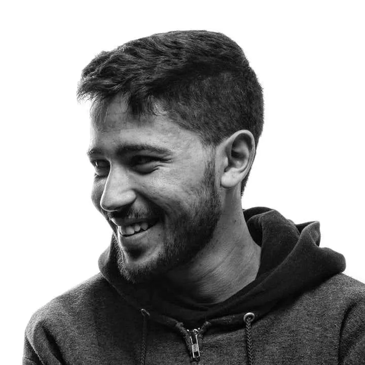 Black and white portrait of Aziz Mrad laughing, wearing a hoodie