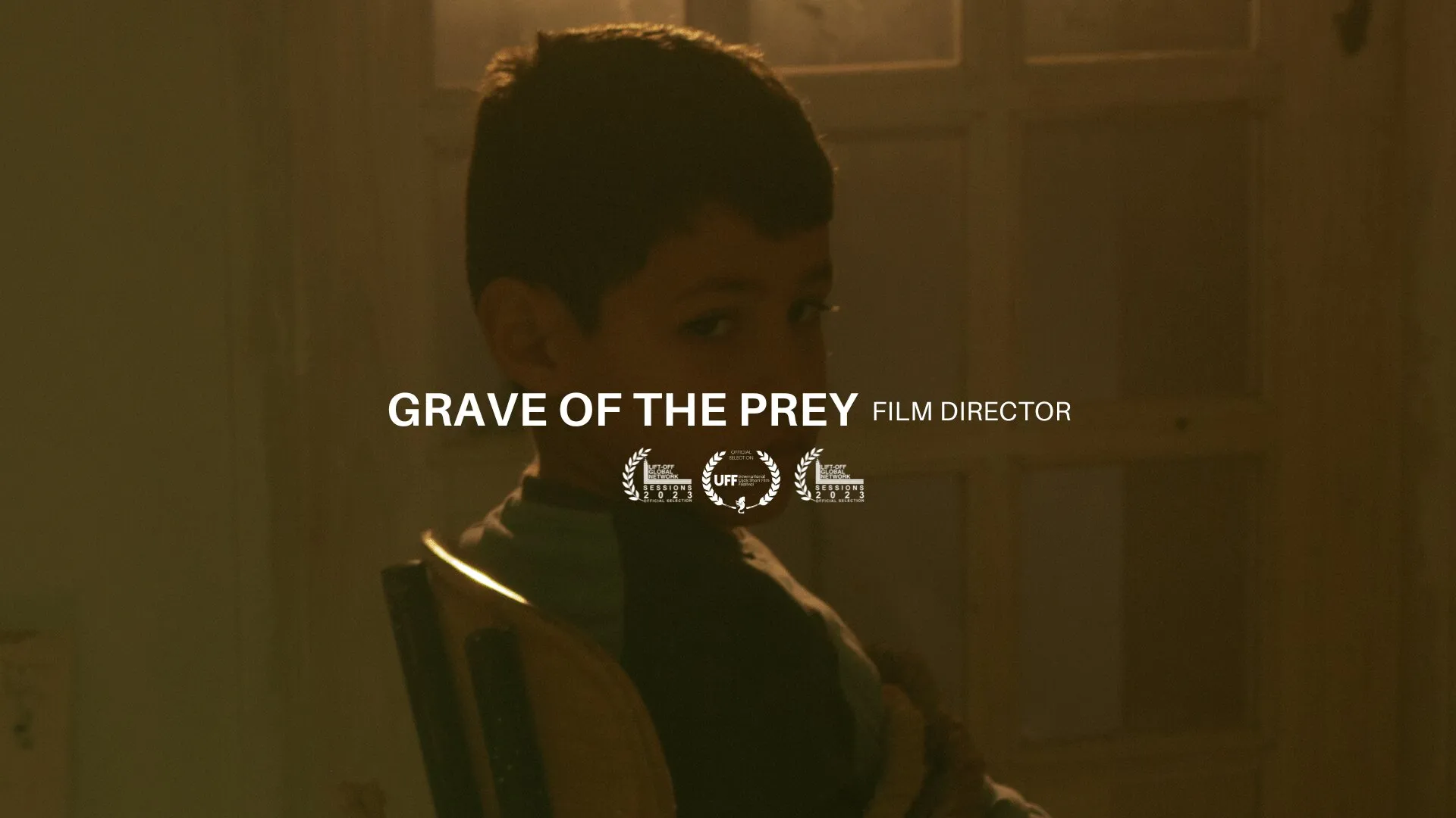 A boy in warm low light looking down, with festival laurels below the title