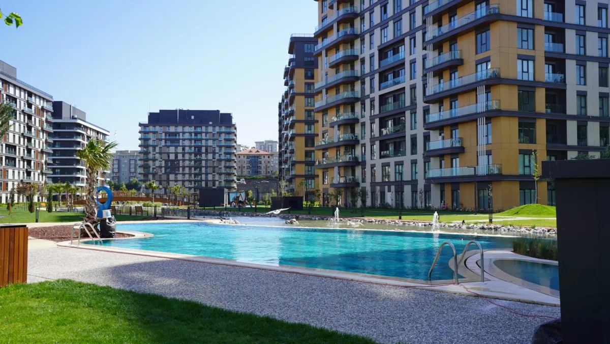 Residential towers framing a turquoise pool and landscaped gardens on a sunny day