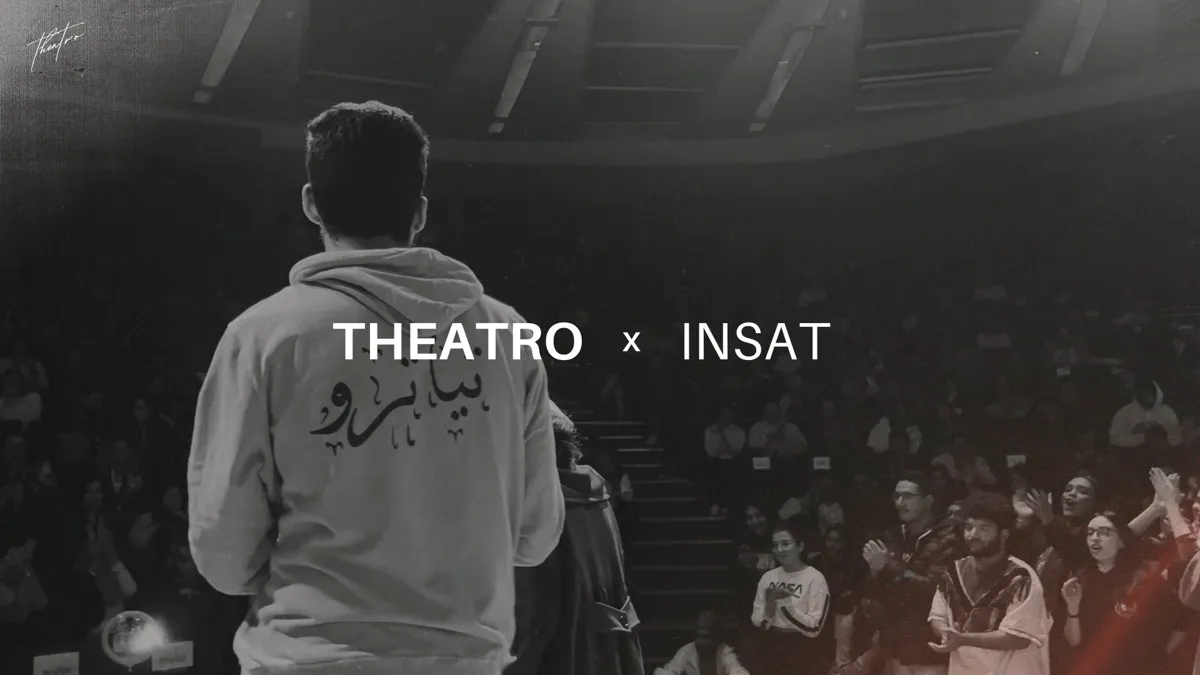 A performer in an Arabic-lettered hoodie facing a packed audience